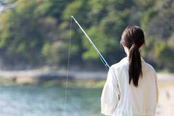 海辺で釣りを楽しむ若い女性