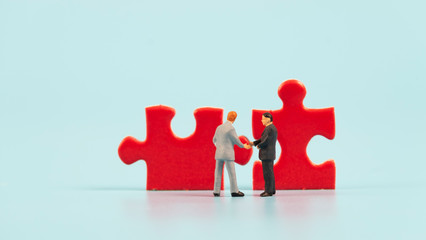 miniature people  shaking hand with jig saw,business concept