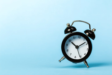 black vintage alarm clock falling to the floor with a colored background