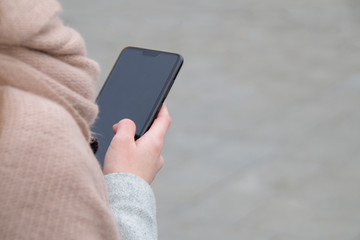 The woman hand holds a smart phone - view over his shoulder. Negative space. Copy space for text.