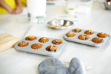 Confectioner took out freshly baked muffins in a baking dish on the table from the oven