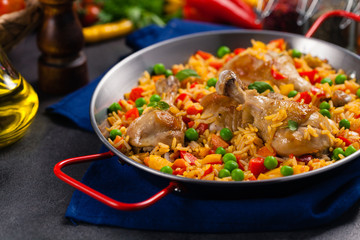 Arroz con pollo. Baked pieces of chicken with bone, rice with paprika and peas.
