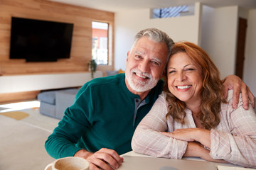 Portrait Of Senior Hispanic Couple At Home Sitting At Table Using Laptop Together