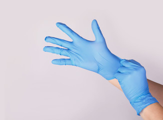 Doctor or nurse putting on blue nitrile surgical gloves, professional medical safety and hygiene...