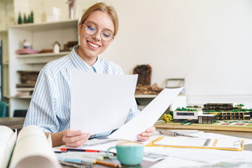 Photo of woman architect working with drawings while designing draft