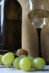 Bottle of wine, glass and grapes on a wooden background