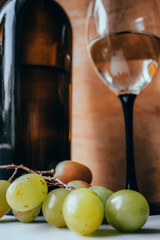 Bottle of wine, glass and grapes on a wooden background