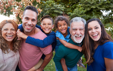 Portrait Of Multi-Generation Hispanic Family Relaxing In Garden At Home Together At Christmas
