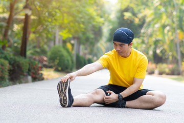 Sporty man stretching leg before workout. Fitness strong male athlete standing outdoor warming up.