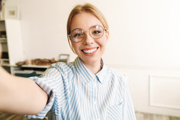 Photo of happy blonde woman smiling while taking selfie photo