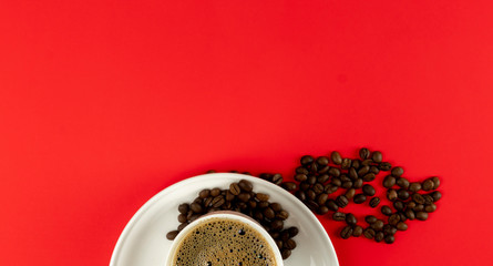 A cup of fresh coffee and coffee beans on a red background. free space for text