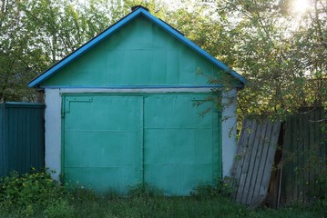 one old white brick garage with a metal gate and a fence in the street