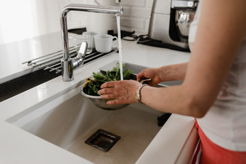 woman washes vegetables,washing vegetables,woman in the kitchen washes vegetables under the pressure of water