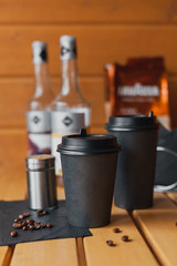 Black glass of takeaway coffee on a wooden background on a sunny day