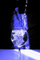 drops of water in a wine glass on a blue background with a ray of light