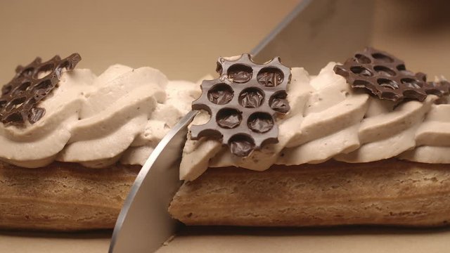 confectioner cuts eclair in a half by knife in slow motion