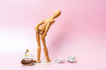 A wooden figure sits on a roll of toilet paper. The concept of a digestive problem.