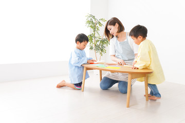 幼稚園で折り紙をする子どもと先生