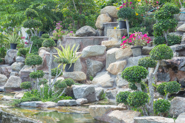 Stone garden with waterfalls and flowers pot decoration in cozy home flower garden on summer.