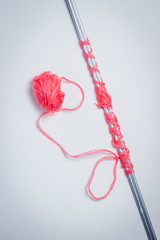 Knitting needles wrapped in scarlet knitting thread. Nearby lies a ball of scarlet knitting thread. Photo on a white background