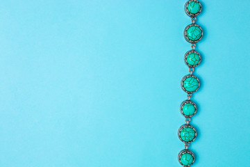 Turquoise bracelet on a blue background with copyspace. Top view.