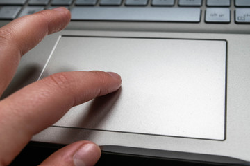 hand on the touchpad on a grey laptop