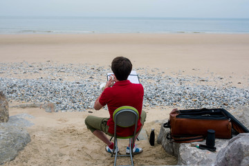 young musician playing alone facing the sea