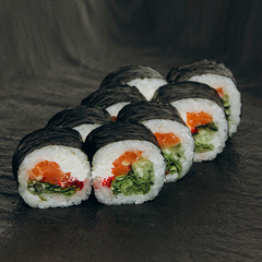 Futomaki with smoked salmon on a black plate