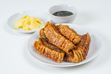Deep Fried Crispy Streaky Pork Belly Thai and Chinese Food on White Plate with Sauce and Ginger on White Background Isolated.