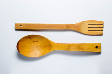 Wooden spoon and wooden fork lie horizontally and parallel to each other on a white background