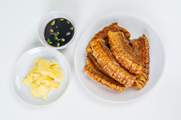 Deep Fried Crispy Streaky Pork Belly Thai and Chinese Food on White Plate with Sauce and Ginger on White Background Isolated.