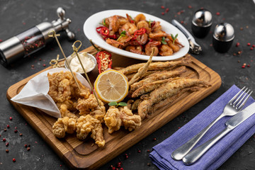 Fish fried in breadcrumbs, seafood. On a black background 