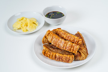 Deep Fried Crispy Streaky Pork Belly Thai and Chinese Food on White Plate with Sauce and Ginger on White Background Isolated.