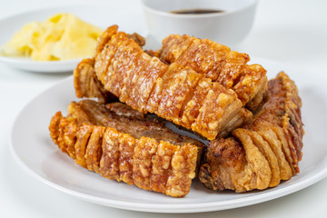 Deep Fried Crispy Streaky Pork Belly Thai and Chinese Food on White Plate with Sauce and Ginger on White Background Isolated.