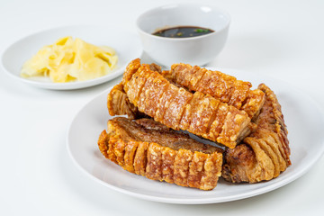 Deep Fried Crispy Streaky Pork Belly Thai and Chinese Food on White Plate with Sauce and Ginger on White Background Isolated.