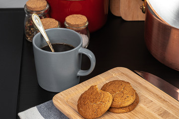 Cup of hot coffee on wooden board on kitchen table close up