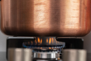 Metal pot on a gas stove burner at home kitchen close up