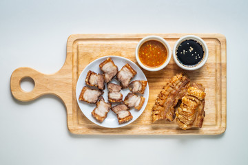Deep Fried Crispy Streaky Pork Belly Thai and Chinese Food on Cutting Board with Sauce and Ginger on White Background Isolated.