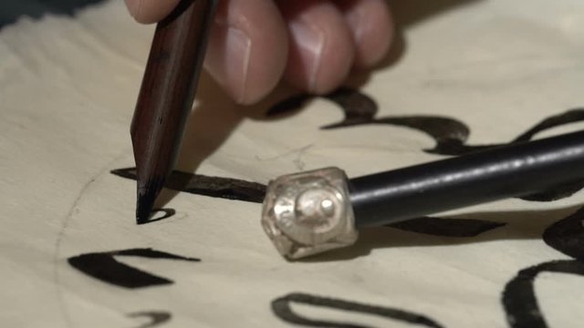 calligrapher writes arabic lettering with calligraphy pen on parchment. macro shot of islamic calligraphy art. close up slider dolly shoting