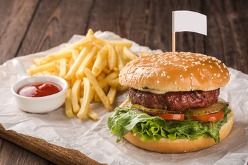 Beef burger served with french fries and tomato ketchup.