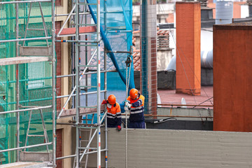 trabajadores subiendo piezas a una obra con una polea 
