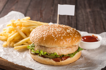 Chicken burger on a wooden board. Served with french fries and tomato ketchup.