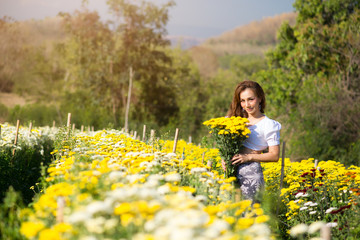 Portrait beautiful asian woman in white dress relaxing at chrysanthemum garden