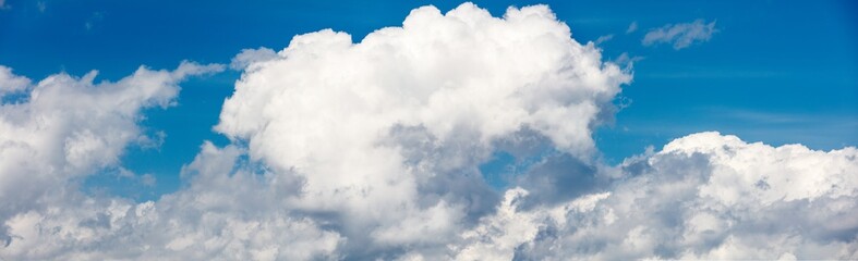 Obraz premium Wide background with copy space with white puffy clouds on a blue sky
