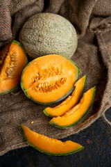 Whole and sliced of Raw organic tuscan melon ,honey melon or cantaloupe (Cucumis melo) on dark  background.Favorite fruit in summer.Food,Fruits or healthcare concept.