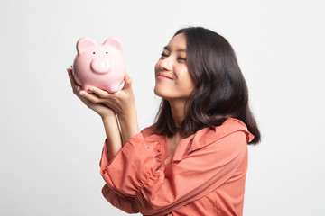 Young Asian woman kiss  a pink coin bank .