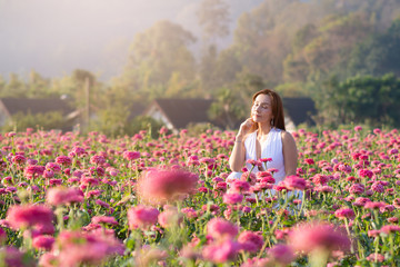 happy young woman enjoying summer in zinnia field. Beautiful woman relaxing in pink flower garden.