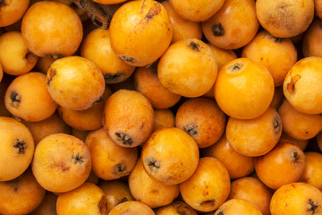 Pile of freshly picked ripe juicy bright orange medlar loquat fruits at farmers market. Local homegrown produce agriculture vitamins healthy diet concept