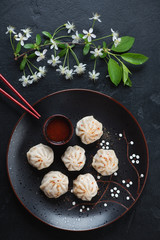 Plate with steamed panasian pork and beef dumplings over black stone background, studio shot, flatlay