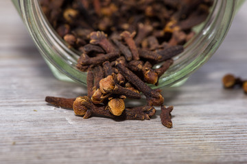 Cloves poured from glass on wooden cutting board